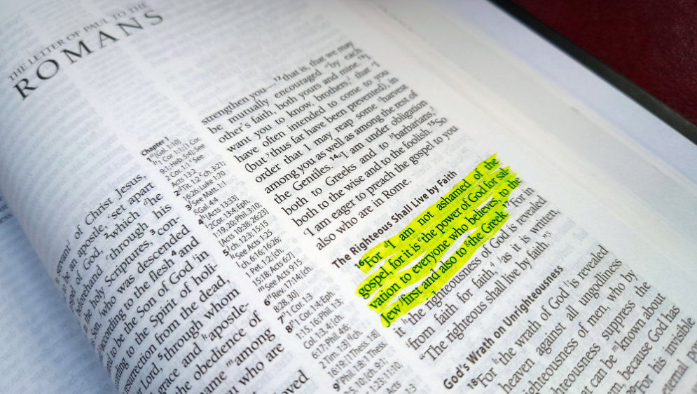 The Bible open with Romans 1v16 highlighted.