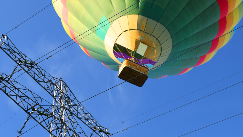 A hot air balloon, perilously close to a pylon.